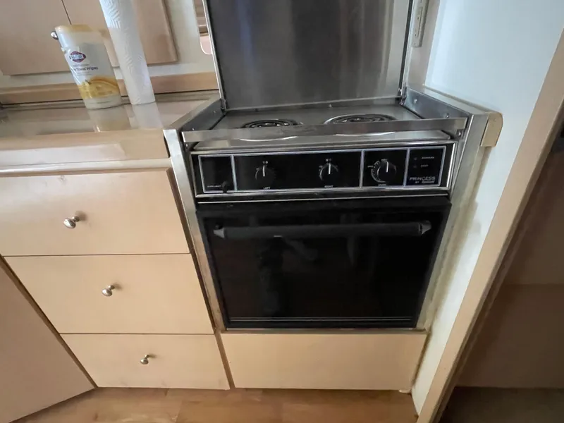 Slide: The Image of 2002 Carver 350 Mariner kitchen with stove and oven, featuring wooden cabinetry. - 26