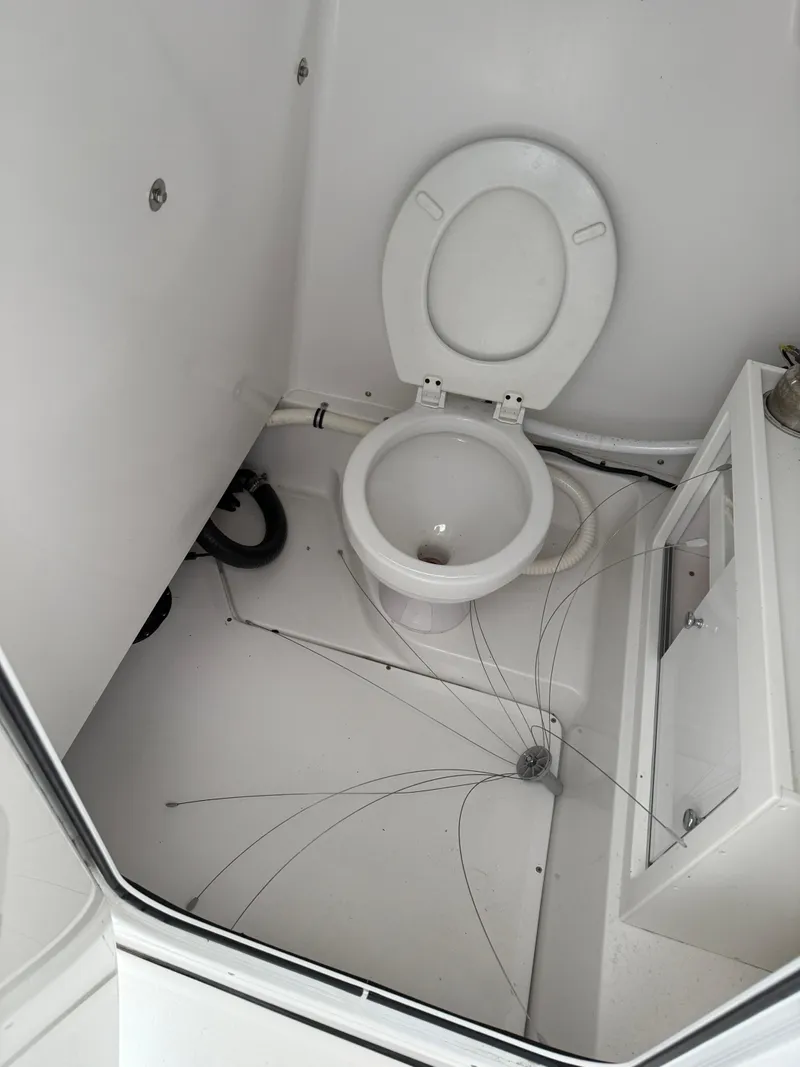 Slide: The Image of 2015 Sportsman Heritage 251 Center Console boat interior with toilet and cracked floor. - 6