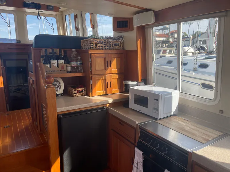 Slide: The Image of Cozy kitchen interior of 2005 Nordic Tug 37 with microwave, fridge, and wooden cabinetry. - 12