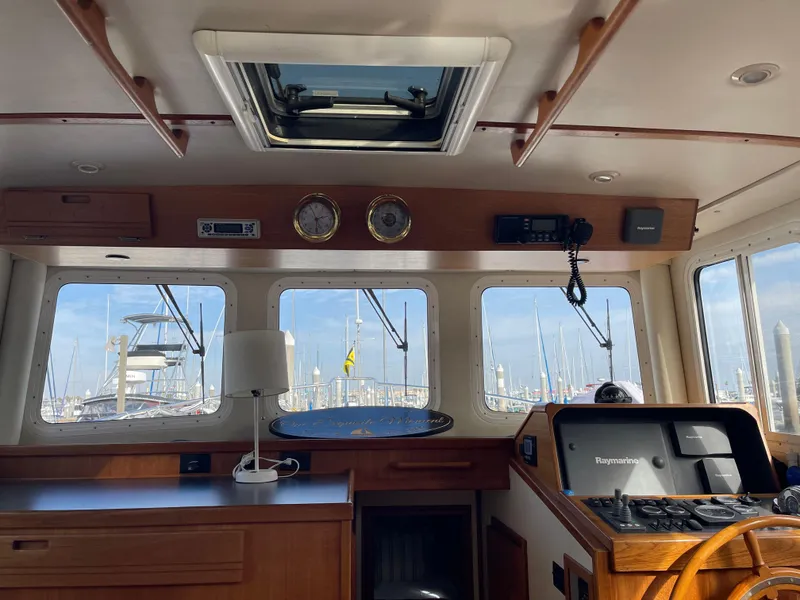 Slide: The Image of 2005 Nordic Tug 37 interior with navigation equipment and marina view through windows. - 16