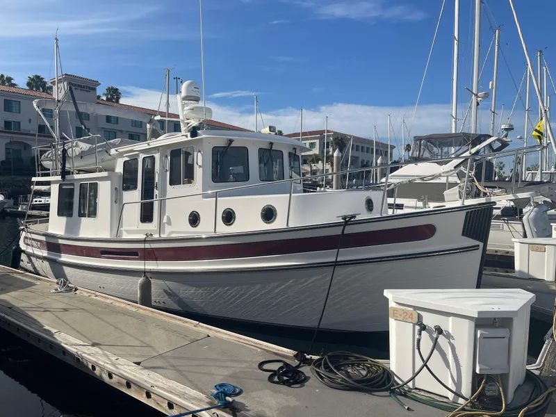 Slide: The Image of 2005 Nordic Tug 37 docked at marina, clear sky, surrounded by other boats. - 2