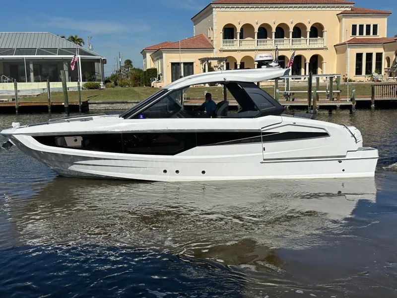 Slide: The Image of 2022 Galeon 325 GTO luxury yacht cruising near waterfront homes. - 1