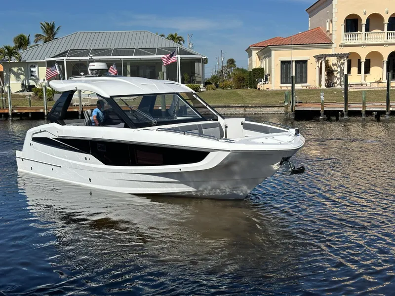Slide: The Image of 2022 Galeon 325 GTO yacht cruising near waterfront homes under a clear blue sky. - 2