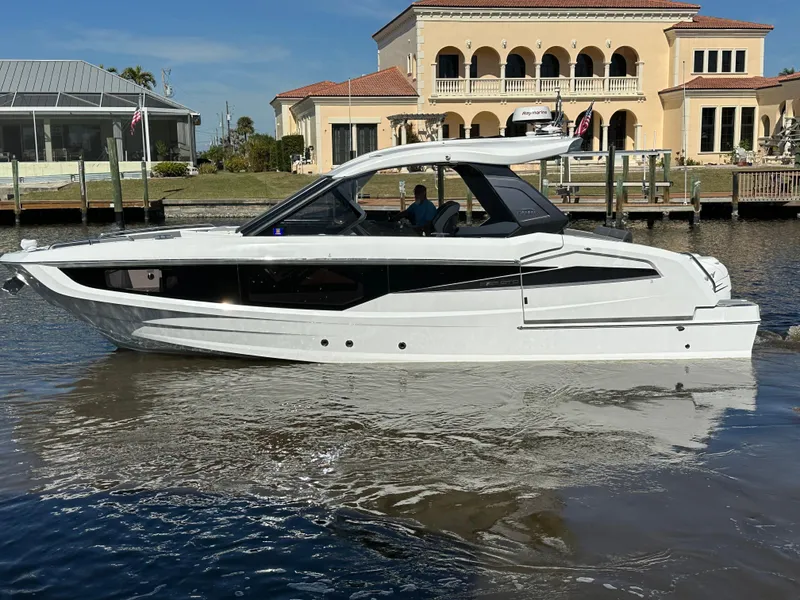 Slide: The Image of 2022 Galeon 325 GTO yacht cruising near waterfront homes. - 24