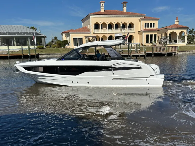 Slide: The Image of 2022 Galeon 325 GTO yacht cruising near luxury waterfront homes. - 9