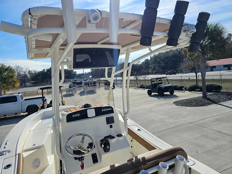 Slide: The Image of 2025 Pioneer 220 Bay Sport boat with console and rod holders, parked outdoors. - 15