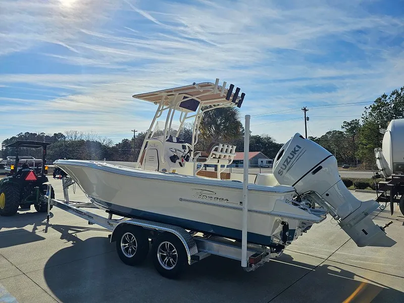 Slide: The Image of 2025 Pioneer 220 Bay Sport boat on trailer with Suzuki outboard motor, parked outdoors. - 7