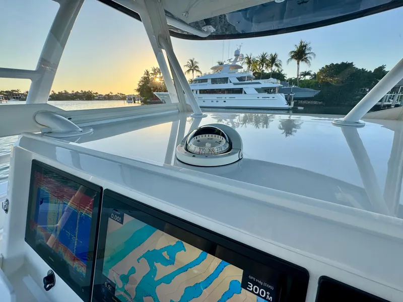 Slide: The Image of 2019 Invincible 37 Catamaran dashboard with navigation screens, compass, and scenic marina view. - 44