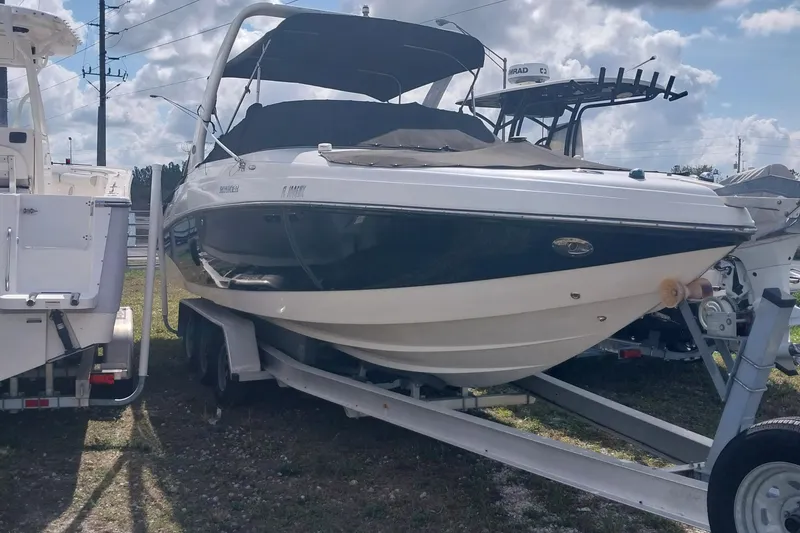 Slide: The Image of 2009 Rinker 296 Captiva Bowrider on trailer, parked outdoors under cloudy sky. - 2