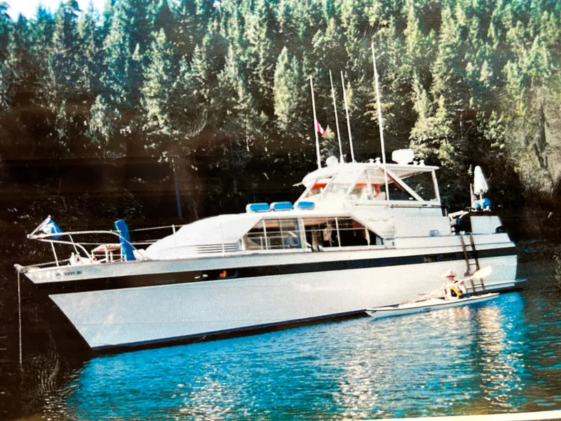 The Image of 1963 Chris-Craft Constellation yacht on serene water with forest backdrop. - 0