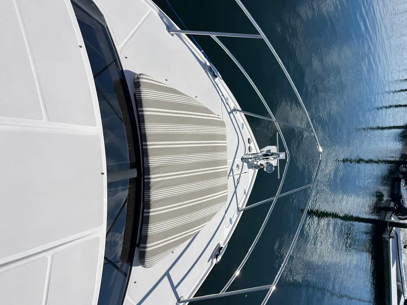 Slide: The Image of 2011 Regal 35 Express Cruiser deck with striped sun pad, docked on calm water. - 19