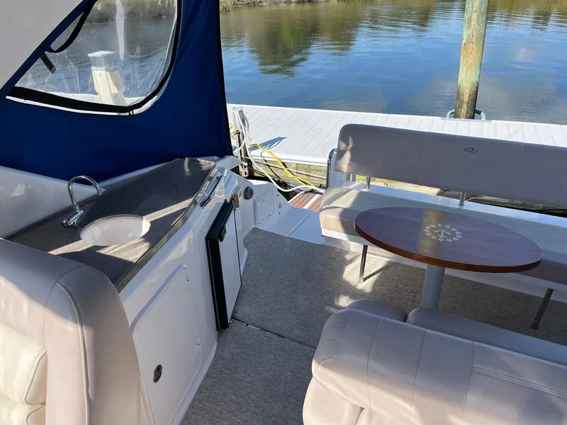 Slide: The Image of 2011 Regal 35 Express Cruiser interior with seating, table, and sink by the water. - 28