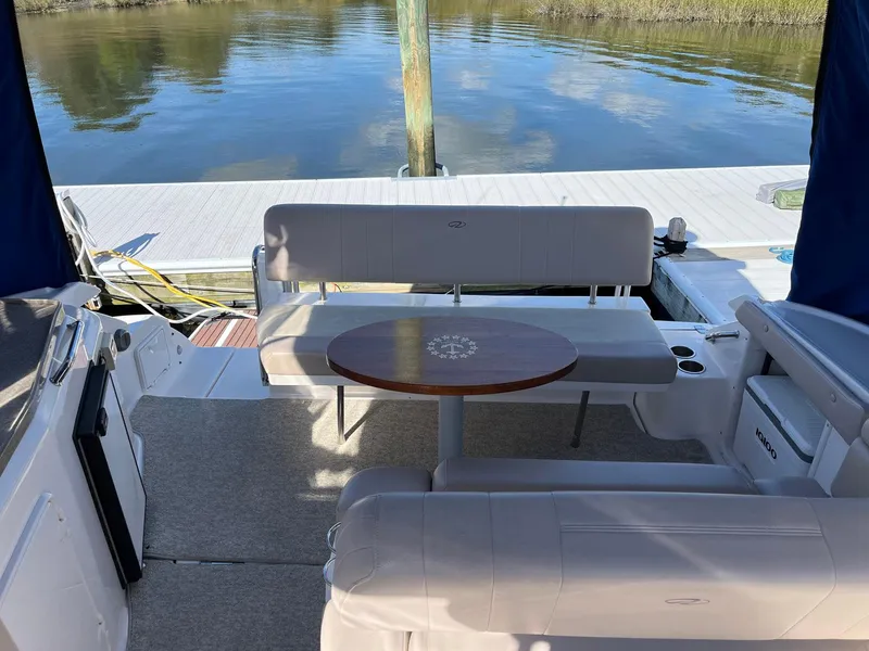 Slide: The Image of 2011 Regal 35 Express Cruiser interior with seating and table, docked by calm waters. - 30