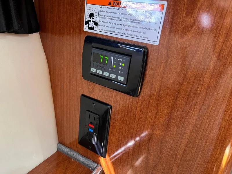 Slide: The Image of Thermostat and outlet on 2011 Regal 35 Express Cruiser's wooden interior panel. - 9