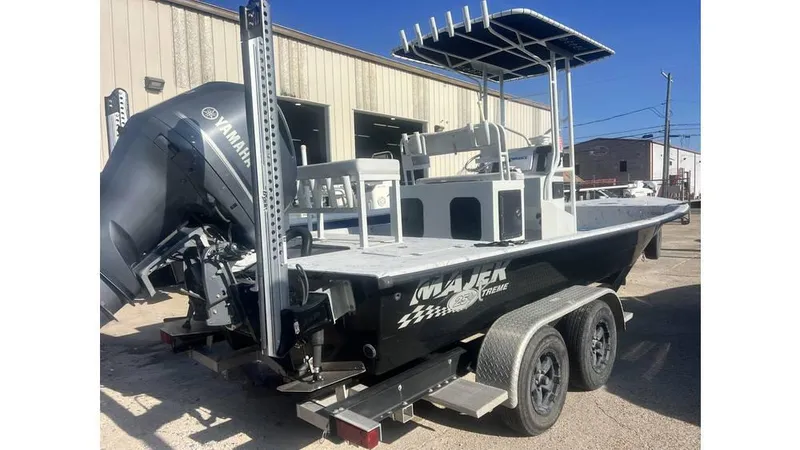 Slide: The Image of 2016 Majek 25 Xtreme boat on trailer, featuring outboard motor and T-top, parked outdoors. - 10