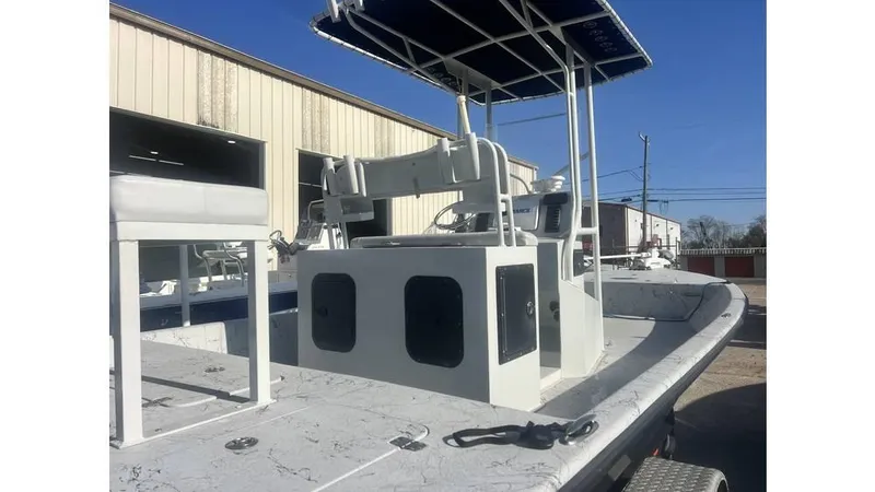 Slide: The Image of 2016 Majek 25 Xtreme boat with T-top and seating, parked near a building. - 3