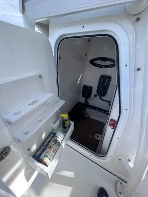 Slide: The Image of 2019 Sportsman Masters 247 Bay Boat interior storage compartment with shelves and equipment. - 23