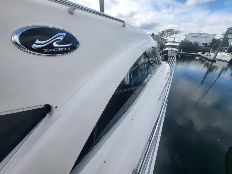 Slide: The Image of 2013 Sea Ray 510 Sundancer yacht docked, showcasing sleek design and reflective water surface. - 34