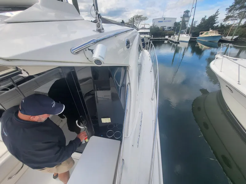 Slide: The Image of 2013 Sea Ray 510 Sundancer docked, man entering cabin, calm marina waters. - 37