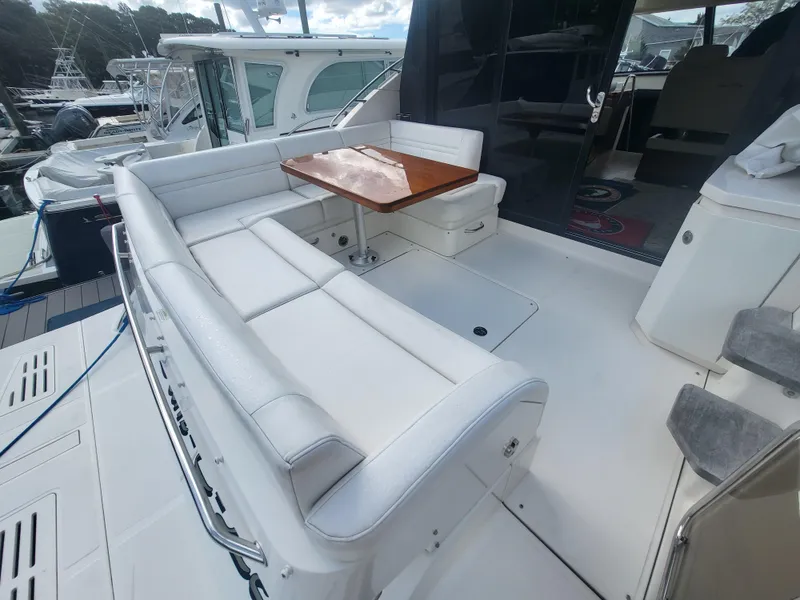 Slide: The Image of 2013 Sea Ray 510 Sundancer yacht with white seating and wooden table on deck. - 44