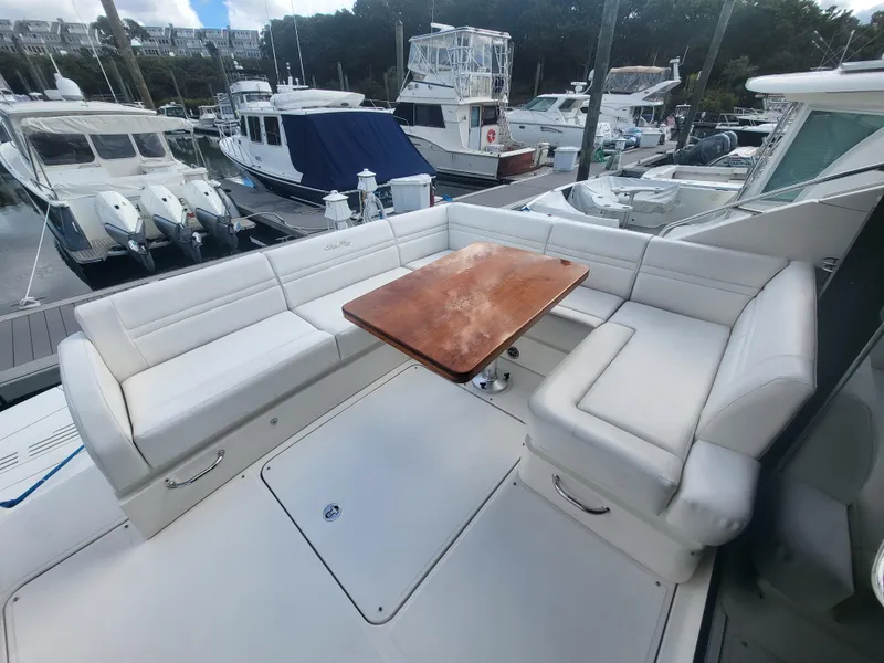Slide: The Image of 2013 Sea Ray 510 Sundancer yacht with spacious outdoor seating and wooden table at marina. - 47