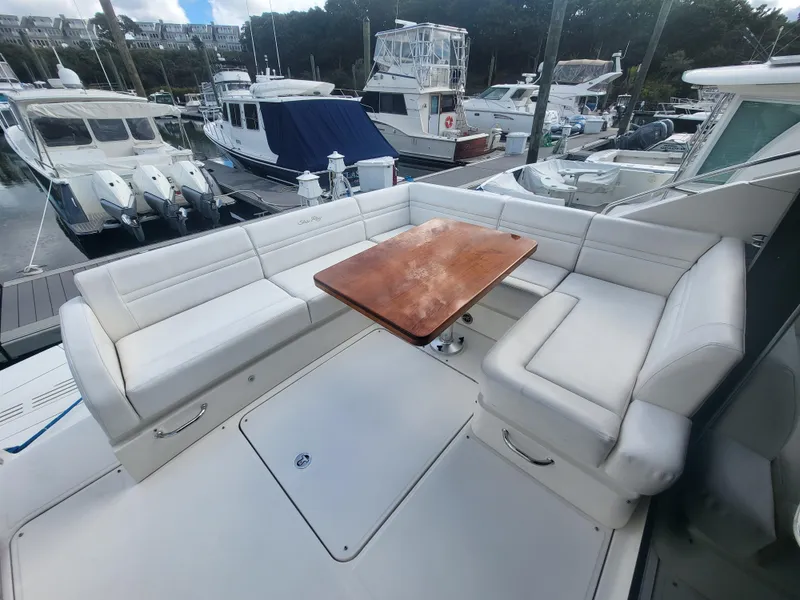 Slide: The Image of 2013 Sea Ray 510 Sundancer yacht with white seating and wooden table at marina. - 48