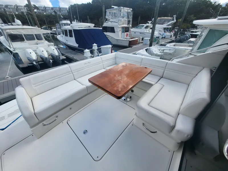 Slide: The Image of 2013 Sea Ray 510 Sundancer yacht with white seating and wooden table at marina. - 49