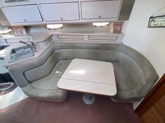 Slide: The Image of 1992 Regal 40 Commodore interior with curved seating and table, featuring a compact kitchen area. - 13