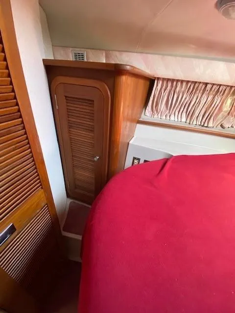 Slide: The Image of Interior of 1992 Regal 40 Commodore with wooden cabinetry and red bedding. - 17