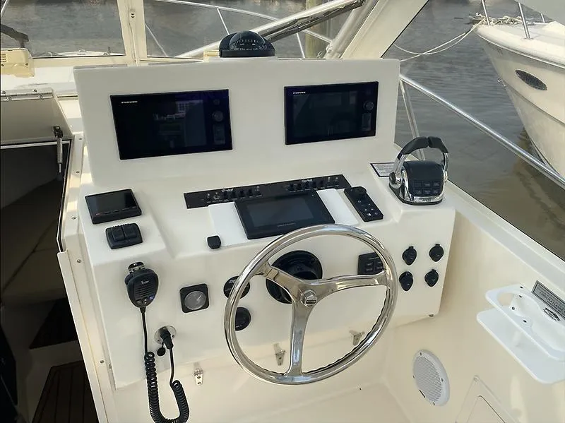Slide: The Image of Control panel of a 2006 Carolina Classic 28 Express boat with steering wheel and navigation equipment. - 11
