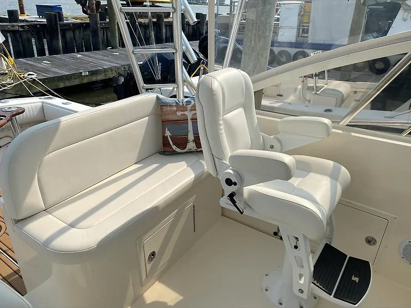 Slide: The Image of 2006 Carolina Classic 28 Express boat interior with white seating and helm chair. - 15