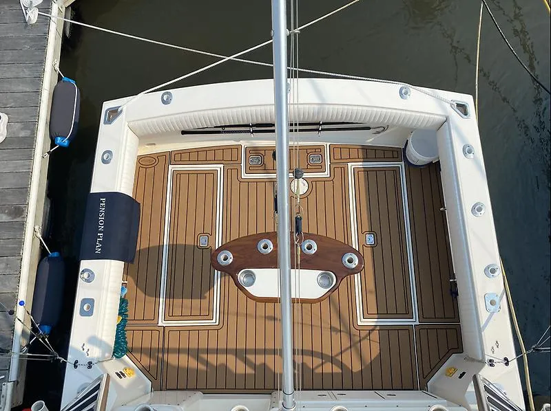Slide: The Image of 2006 Carolina Classic 28 Express boat deck with wood finish and fishing rod holders. - 17