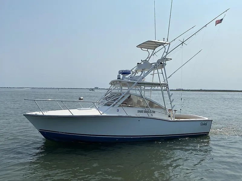 Slide: The Image of 2006 Carolina Classic 28 Express boat on calm water, featuring a sleek design and fishing equipment. - 4