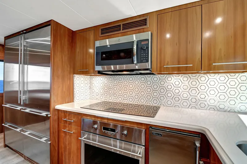 Slide: The Image of Luxurious 2005 Hatteras Semi-Displacement yacht kitchen with modern appliances and hexagonal tile backsplash. - 13