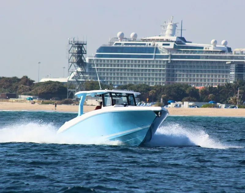 Slide: The Image of 2025 Fountain 38 SCX boat cruising near a large cruise ship on open water. - 4