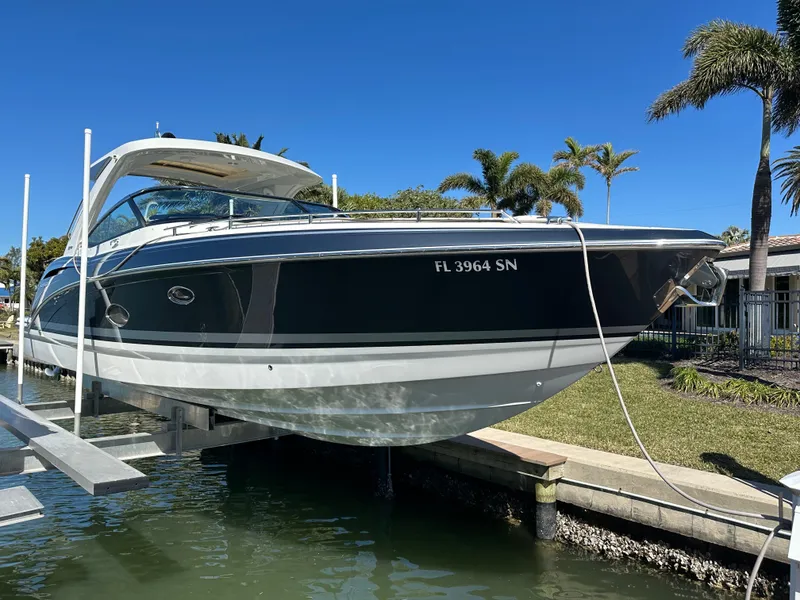 Slide: The Image of 2020 Formula 350 Crossover Bowrider OB on lift, docked by palm trees. - 4