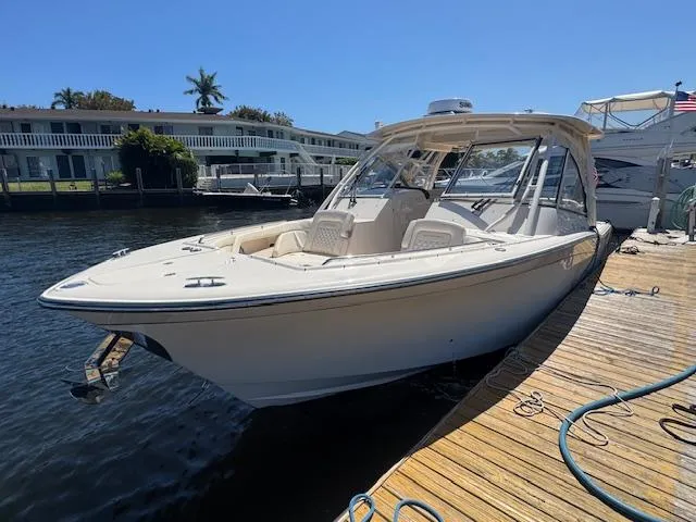 The Image of 2024 Grady-White Freedom 335 boat docked on a calm waterfront with palm trees. - 0