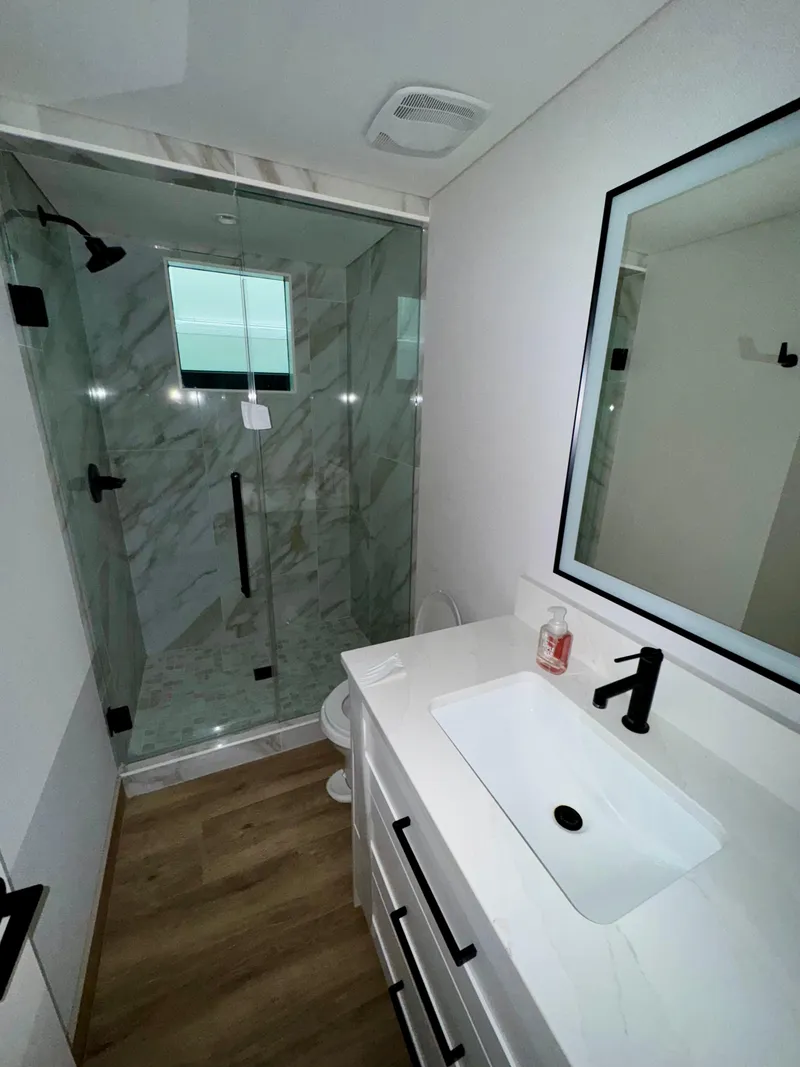 Slide: The Image of Modern bathroom in Adonia Cosmos Trip #11, 2024 model, featuring glass shower and sleek vanity. - 11