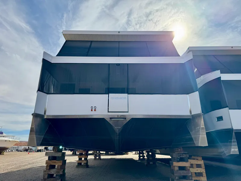 Slide: The Image of Modern Adonia Cosmos Trip #11 houseboat, 2024 model, elevated on blocks under a sunny sky. - 2
