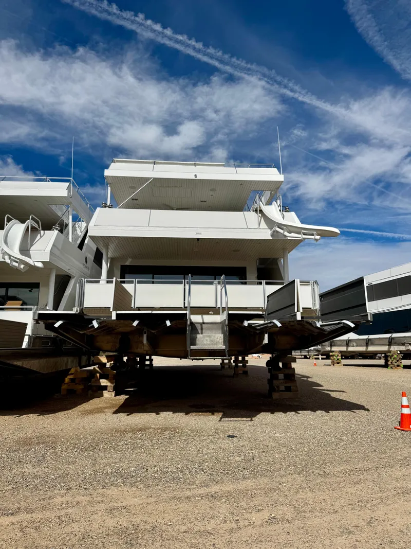 Slide: The Image of Modern Adonia Cosmos Trip #11 houseboat, 2024 model, on dry land under a blue sky. - 3