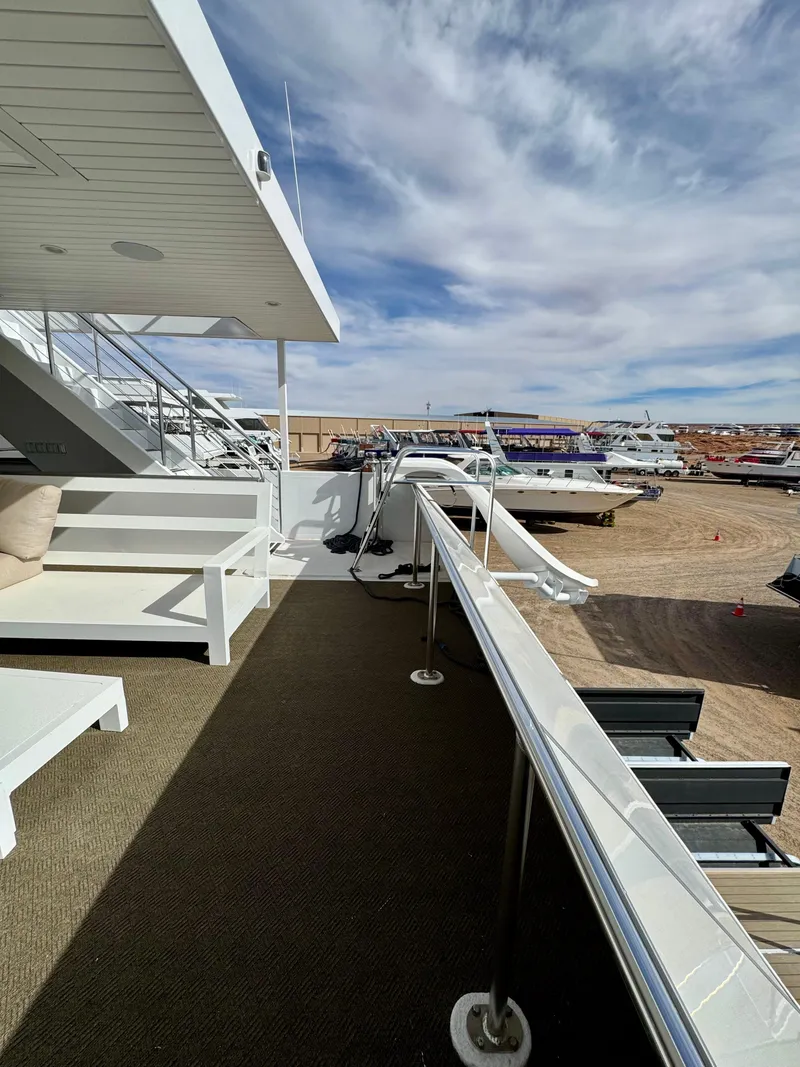 Slide: The Image of Upper deck view of Adonia Cosmos Trip #11 yacht, 2024 model, docked under a cloudy sky. - 32