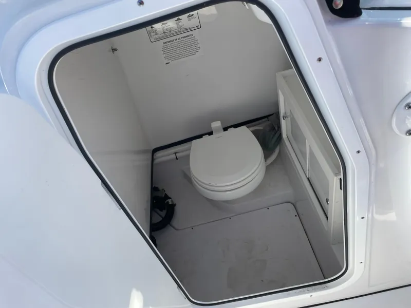 Slide: The Image of 2021 Sportsman Open 282 Center Console boat interior with compact marine toilet. - 9