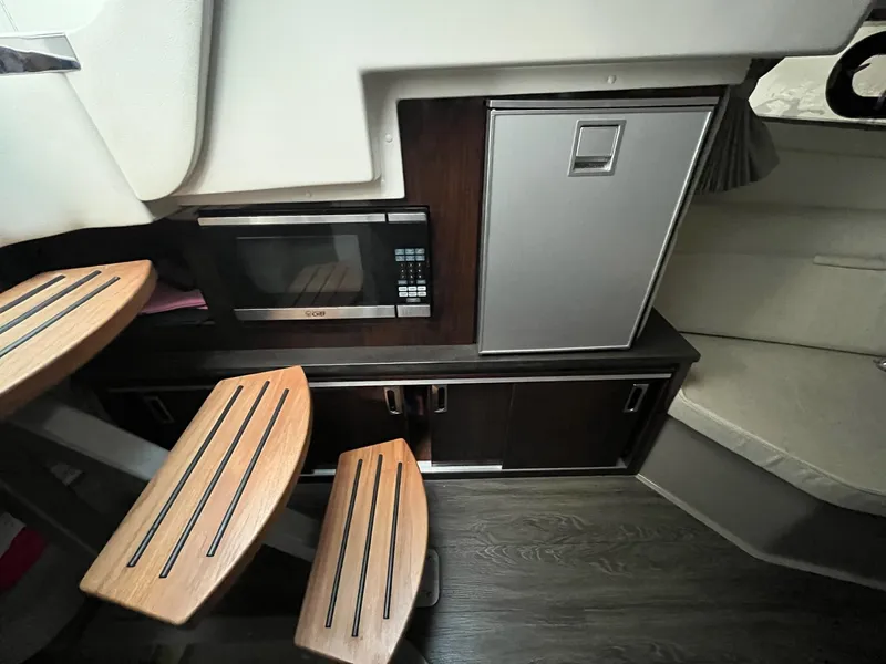 Slide: The Image of Interior of 2020 Sea Ray Sundancer 320 with microwave, fridge, and wooden steps. - 23