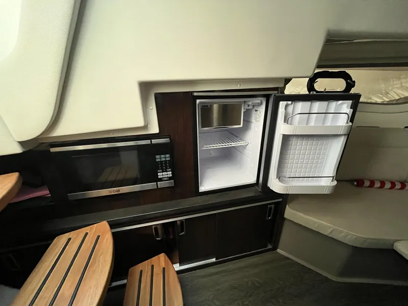 Slide: The Image of 2020 Sea Ray Sundancer 320 interior with microwave, fridge, and seating area. - 24