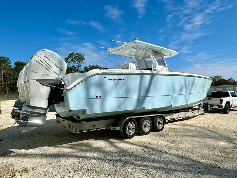 The Image of 2020 Invincible 37 Catamaran on trailer, light blue hull, dual outboard engines, parked outdoors. - 0