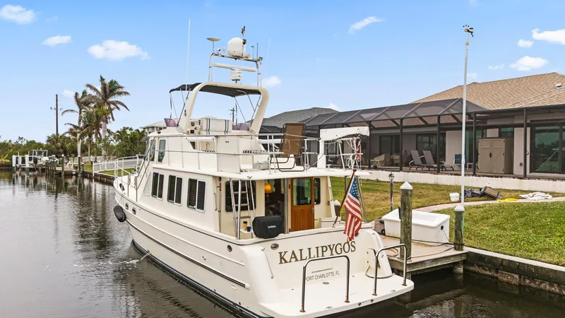 Slide: The Image of 2008 North Pacific 43 Pilothouse yacht docked by a canal with American flag. - 1