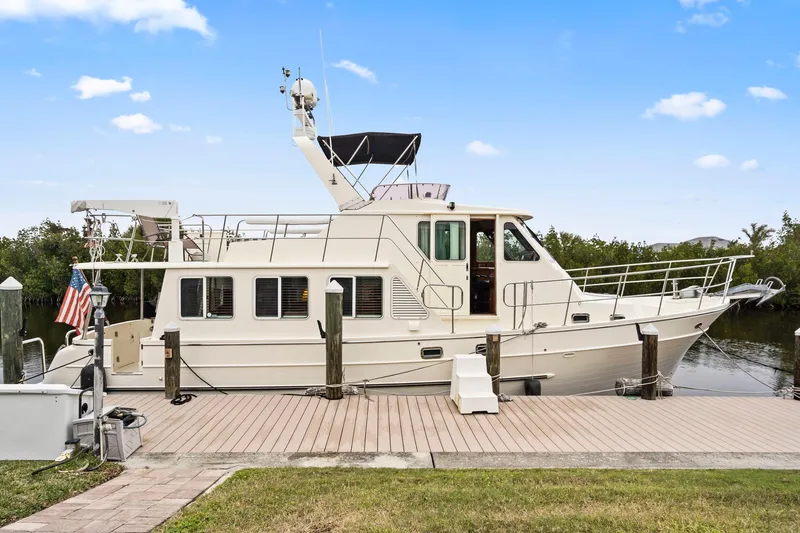 Slide: The Image of 2008 North Pacific 43 Pilothouse yacht docked by a wooden pier. - 48