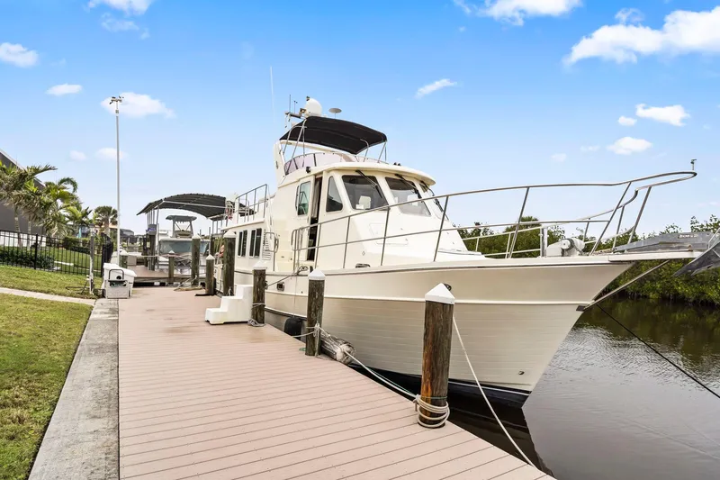 Slide: The Image of 2008 North Pacific 43 Pilothouse yacht docked by a serene waterfront. - 49
