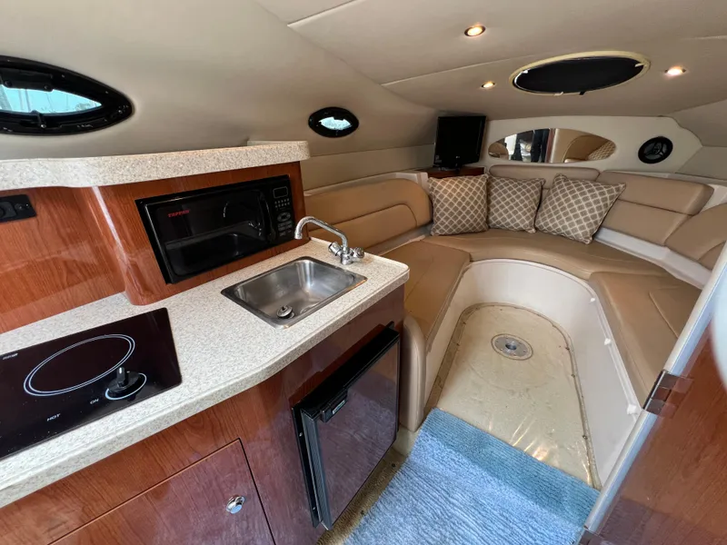 Slide: The Image of 2008 Regal 2665 boat interior with kitchenette, sink, and cozy seating area. - 16