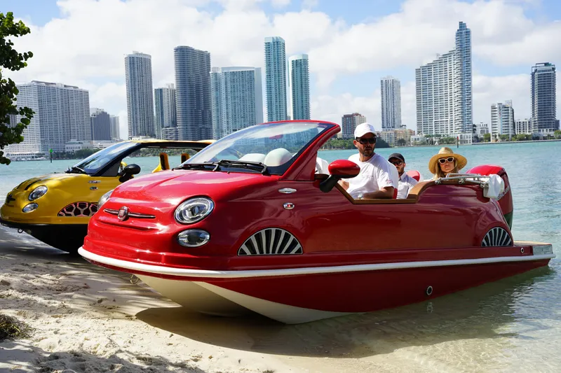 Slide: The Image of 2025 Car Off-shore Fiat 500 Classic amphibious vehicles on beach, city skyline in background. - 10
